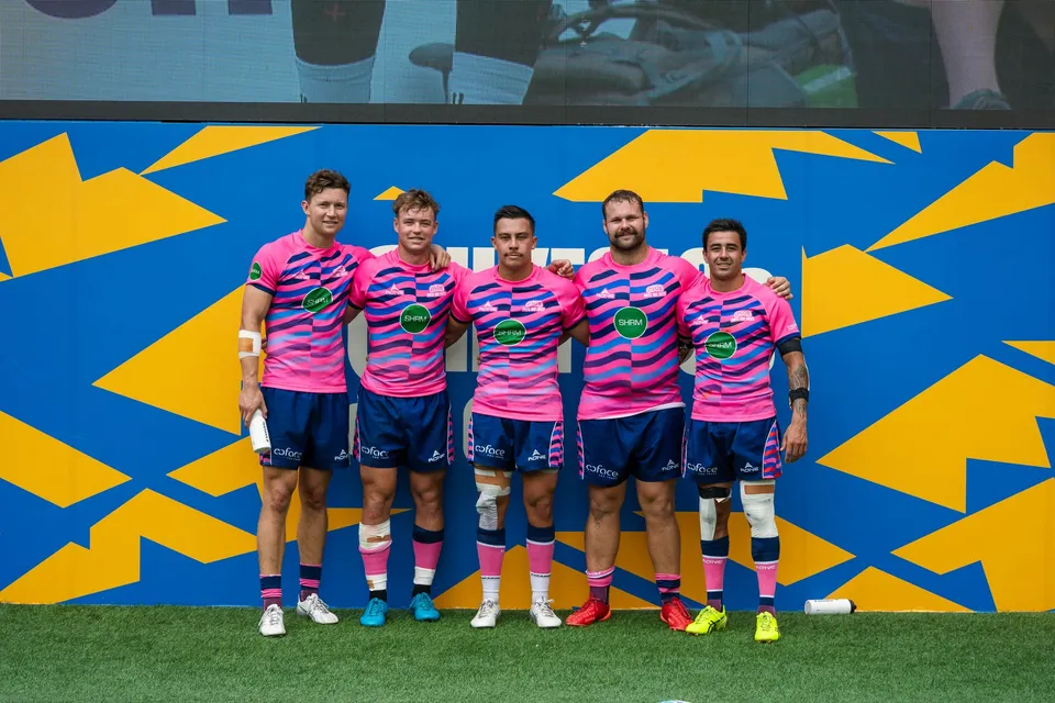Five OSOB players in pink kit in front of the HKFC 10s backdrop