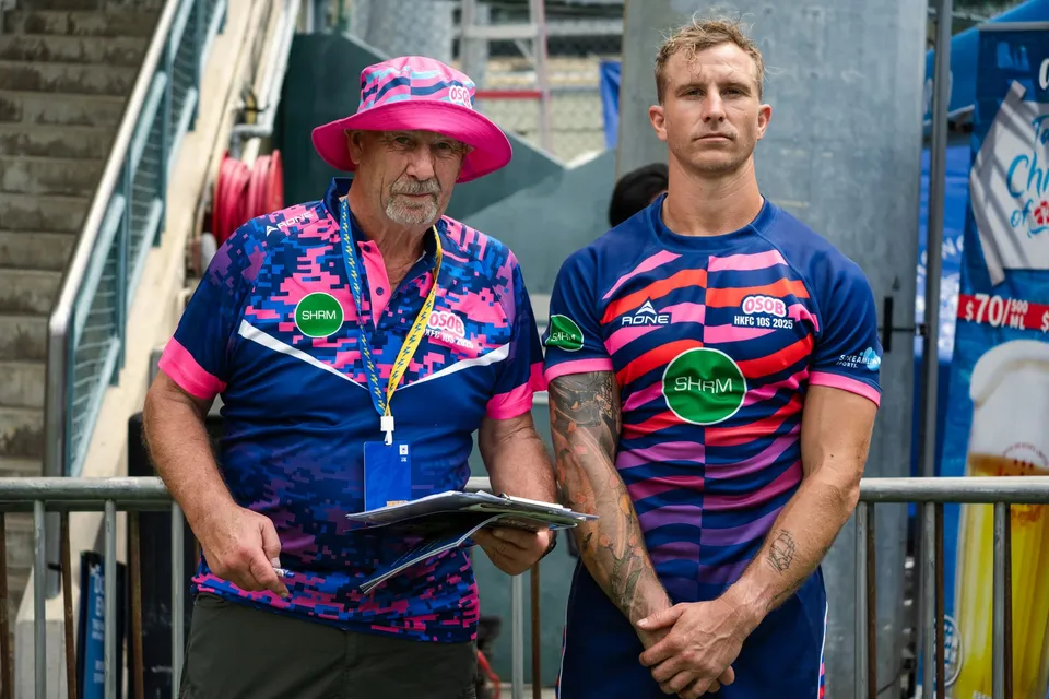 An OSOB coach in a pink bucket hat stands beside a player