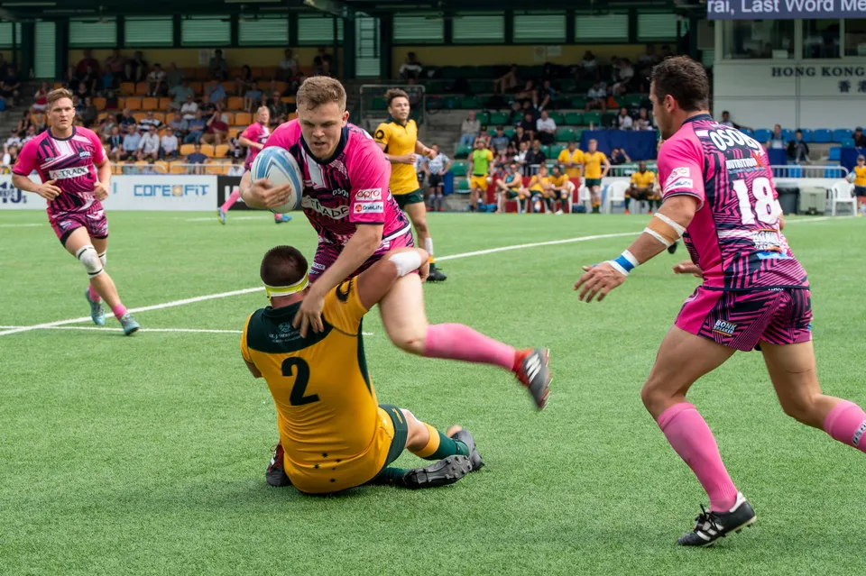 OSOB ball carrier in pink is brought down by a Wallabies defender in number 2 as teammate 18 runs in