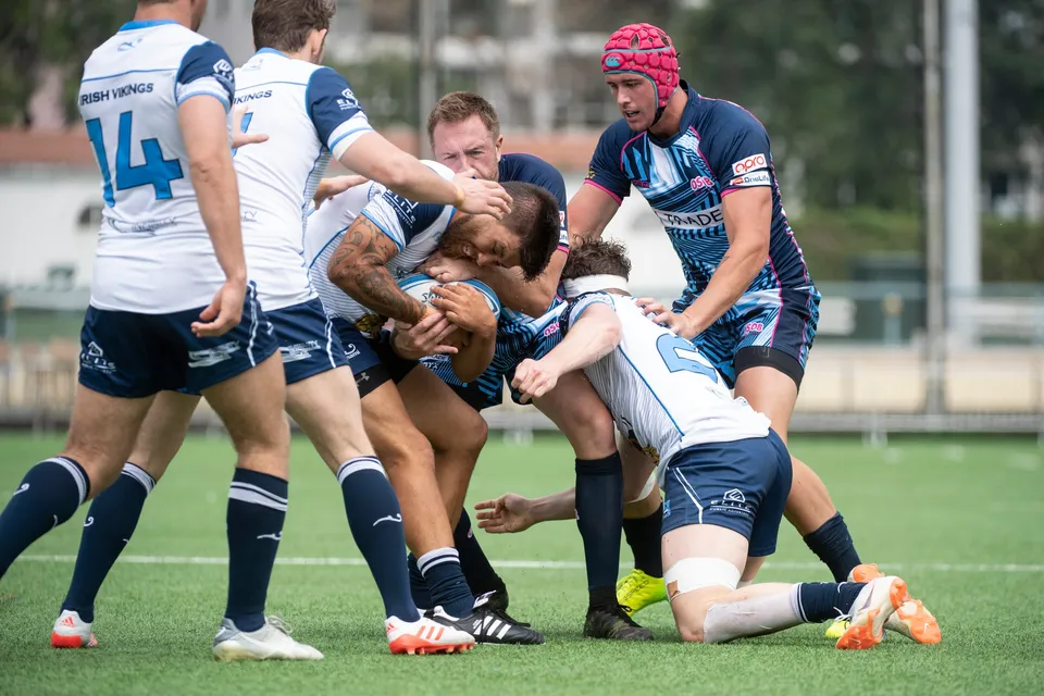 Irish Vikings ball carrier in white is held up in a crowded tackle by OSOB defenders, 2019