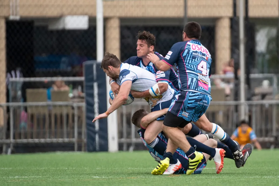 Irish Vikings player in white is wrapped up in a tackle by OSOB players, one wearing number 4, 2019