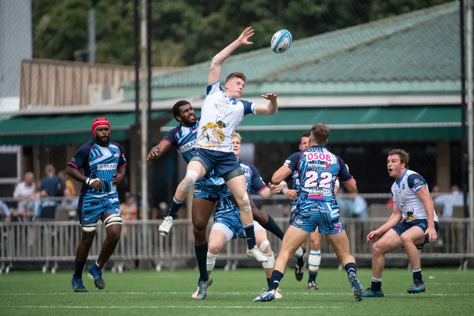 Irish Vikings player in white leaps high with arms stretched for the ball while OSOB players contest it in the air