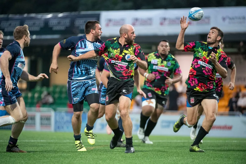 Floral-shirted player leaps to catch a high ball as team-mates and blue-striped opponents look on, 2019 YCAC