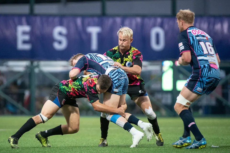 Two floral-shirted players tackle a blue-striped runner low while a player in number 16 stands by, 2019 YCAC
