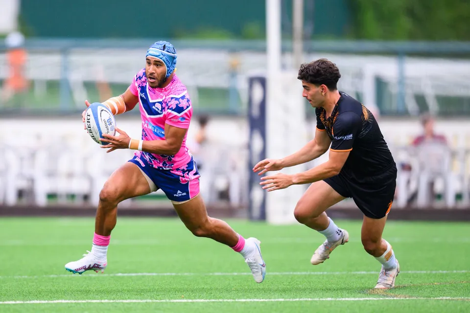 OSOB ball carrier in a blue headguard sprints past an Ashbury Tropics defender in black reaching out to tackle