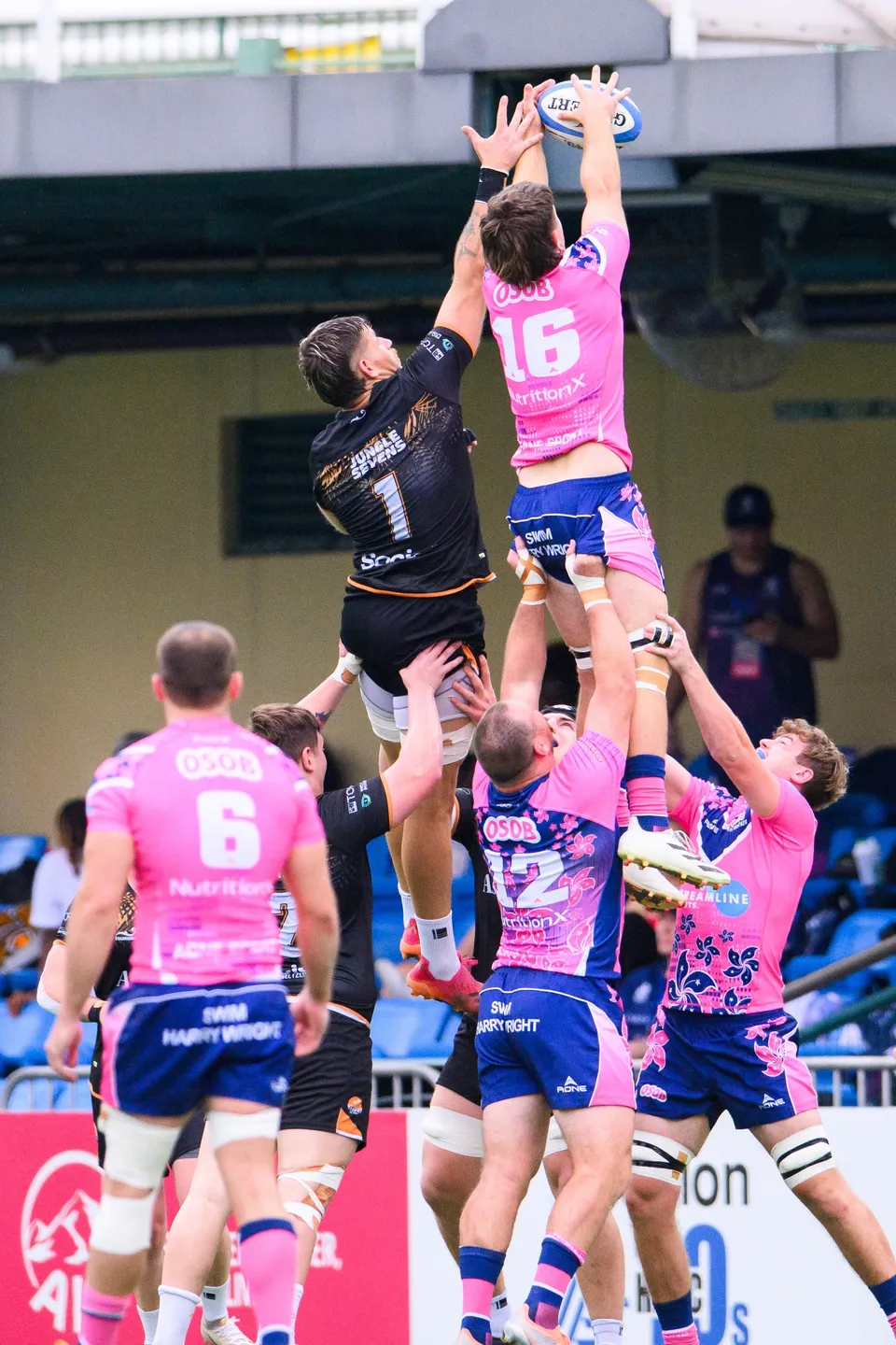 OSOB number 16 is lifted high to win a line-out against Ashbury Tropics number 1 while teammates support below
