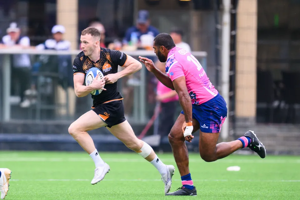 Ashbury Tropics runner with the ball sprints along the pitch with an OSOB defender chasing at his shoulder