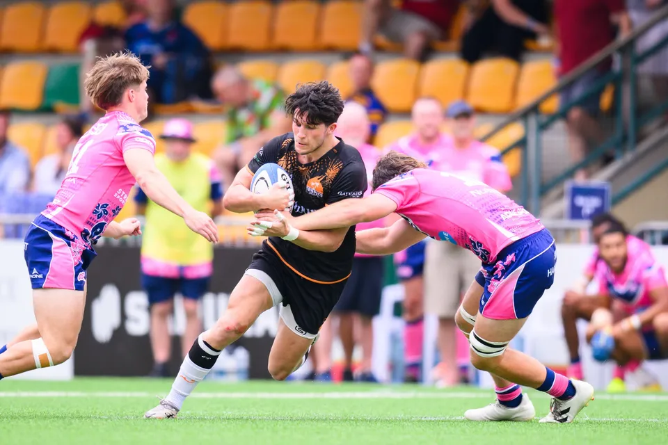 Ashbury Tropics ball carrier is tackled at the waist by an OSOB player while a second OSOB player covers