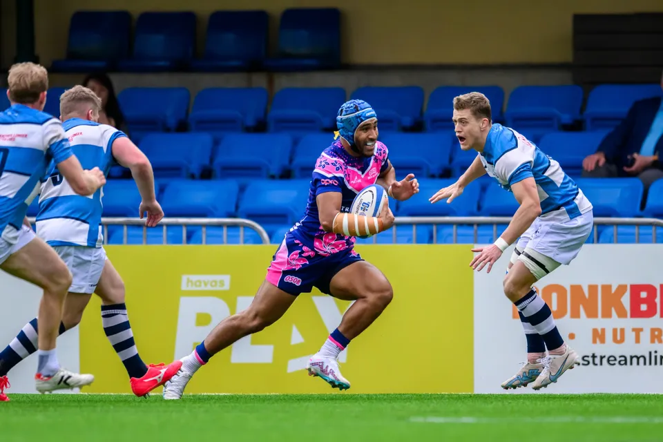 OSOB player in a blue headband runs with the ball past HKFC Natixis defenders in light blue and white