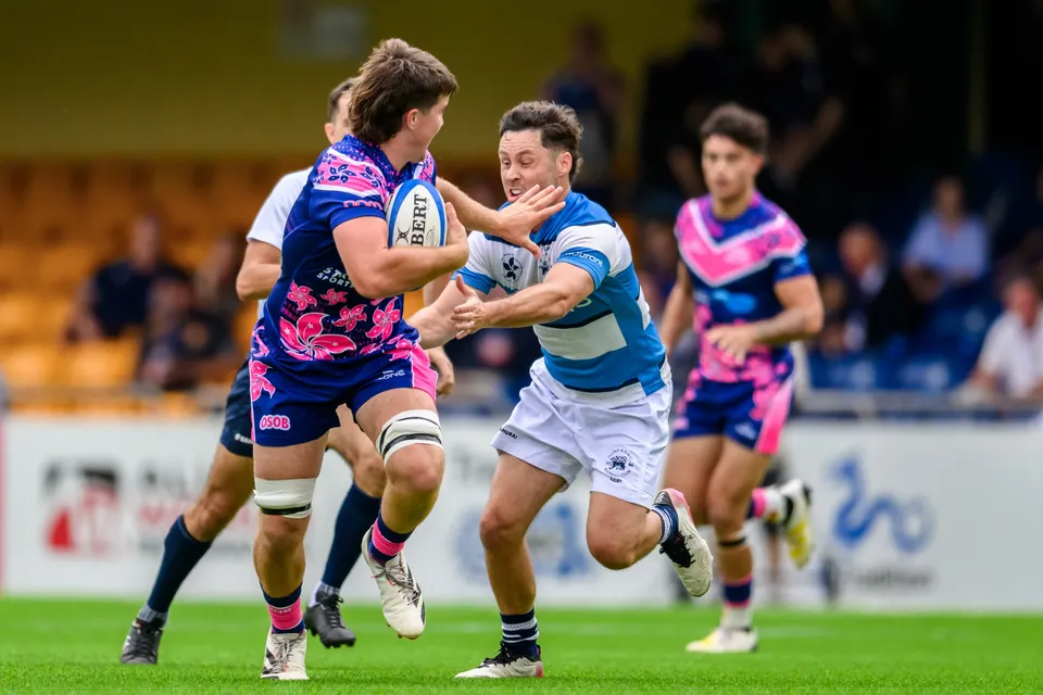 OSOB ball carrier runs at pace in front of the orange stand as an HKFC Natixis defender reaches to tackle