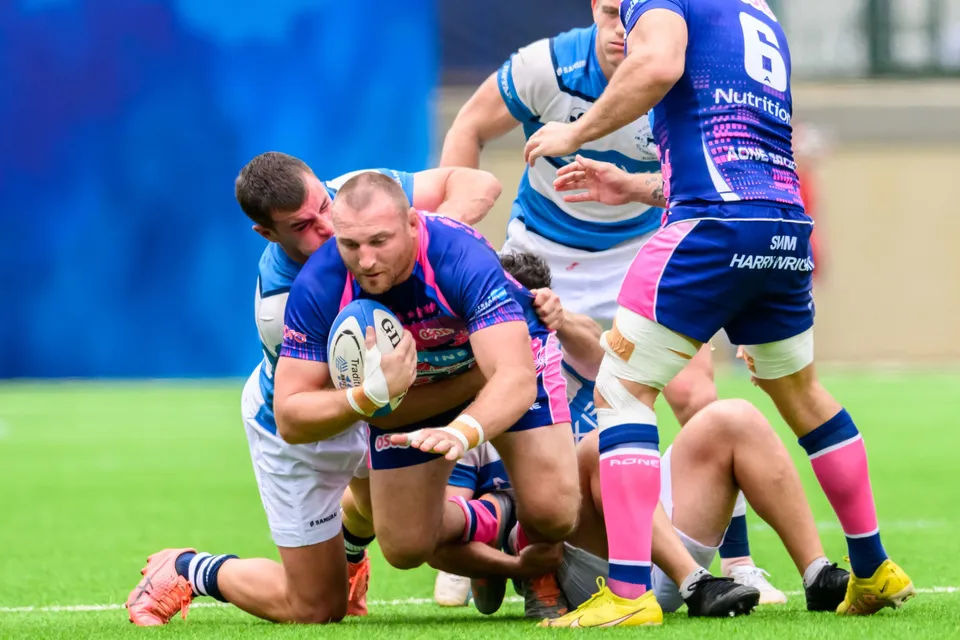OSOB forward is dragged to the turf by HKFC Natixis tacklers while an OSOB number 6 runs in to support