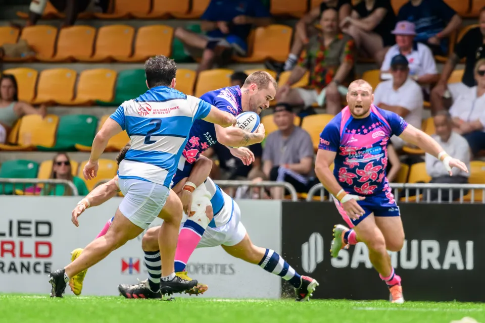 HKFC Natixis number 2 carries the ball into contact with an OSOB tackler while another OSOB player waits at right