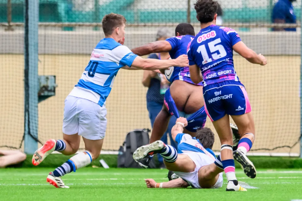OSOB number 15 runs forward while a fallen HKFC Natixis player lies on the turf and a number 10 reaches out