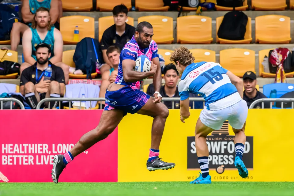 OSOB runner carries the ball in one hand along the touchline as an HKFC Natixis number 15 closes in