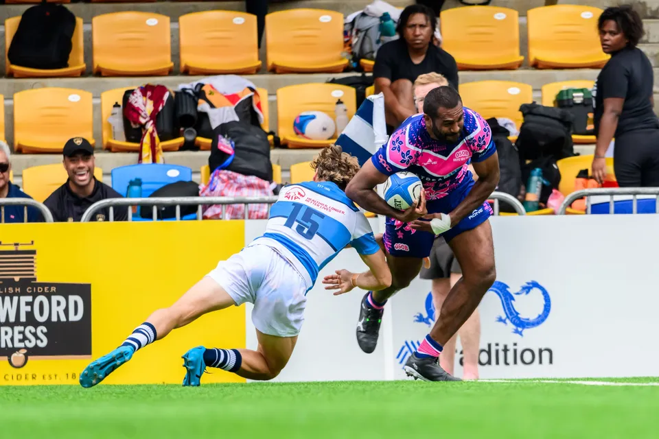 OSOB runner with the ball swerves past a diving HKFC Natixis number 15 near the touchline