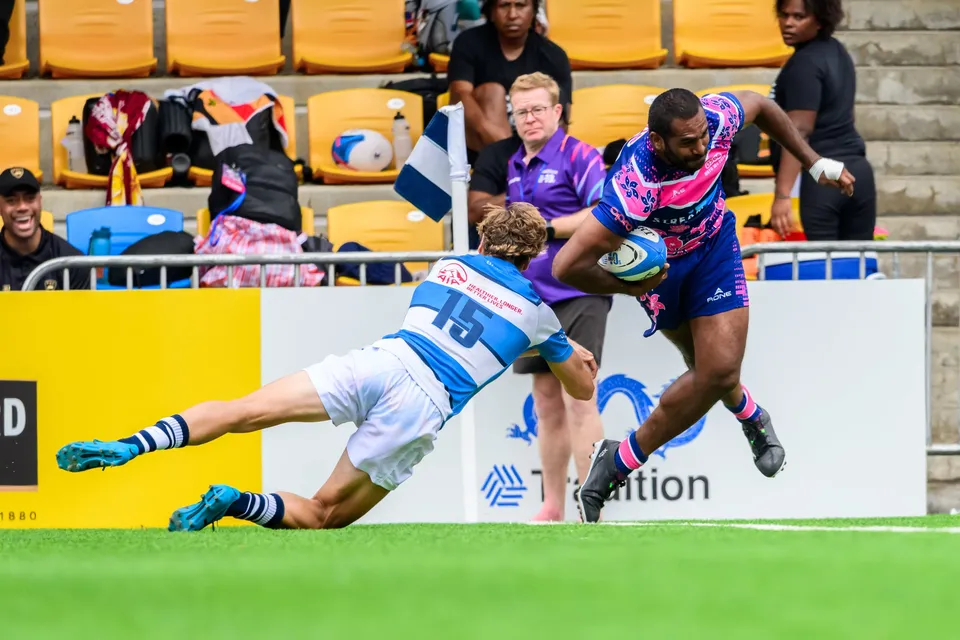 OSOB ball carrier races along the touchline as HKFC Natixis number 15 dives and misses, steward in purple behind