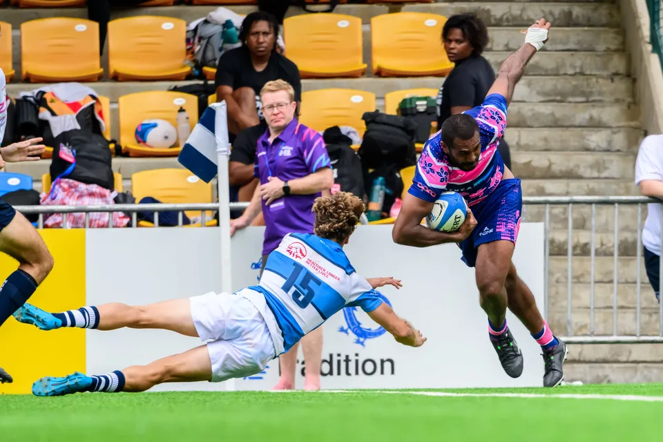 OSOB runner leaps clear of a stretched-out HKFC Natixis number 15, one arm raised above the ball