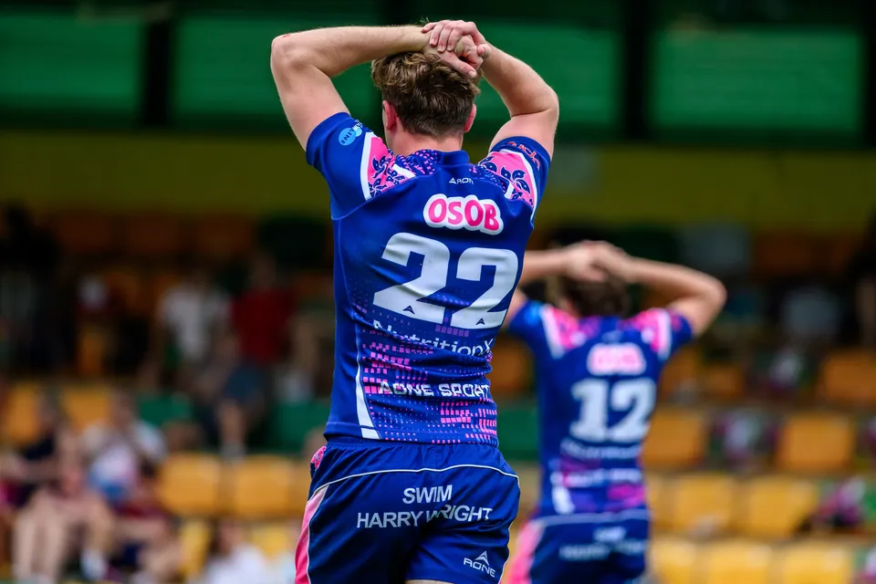 Two OSOB players seen from behind, number 22 with both hands on his head and number 12 behind him