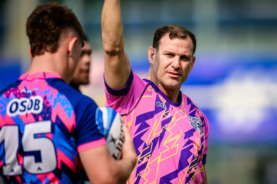 OSOB number 15 holds the ball in the foreground as a pink-shirted official beside him raises one arm