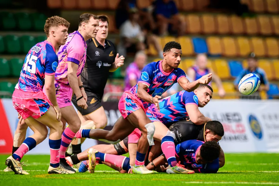 OSOB scrum-half passes the ball out from a ruck against Ashbury Tropics, players crowded around the breakdown