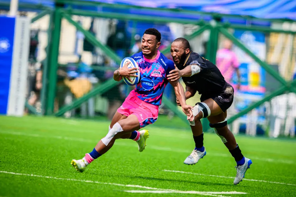 OSOB player runs with the ball under one arm as a black-shirted Tropics defender chases from behind