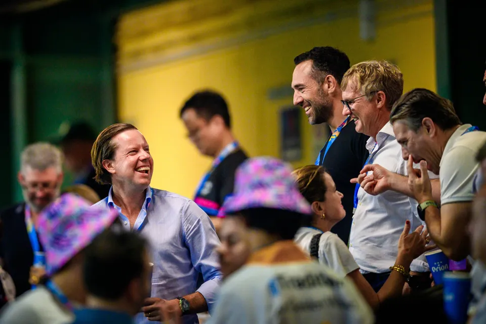 Several men in the crowd laugh and talk in front of a yellow wall at the 2026 HKFC 10s