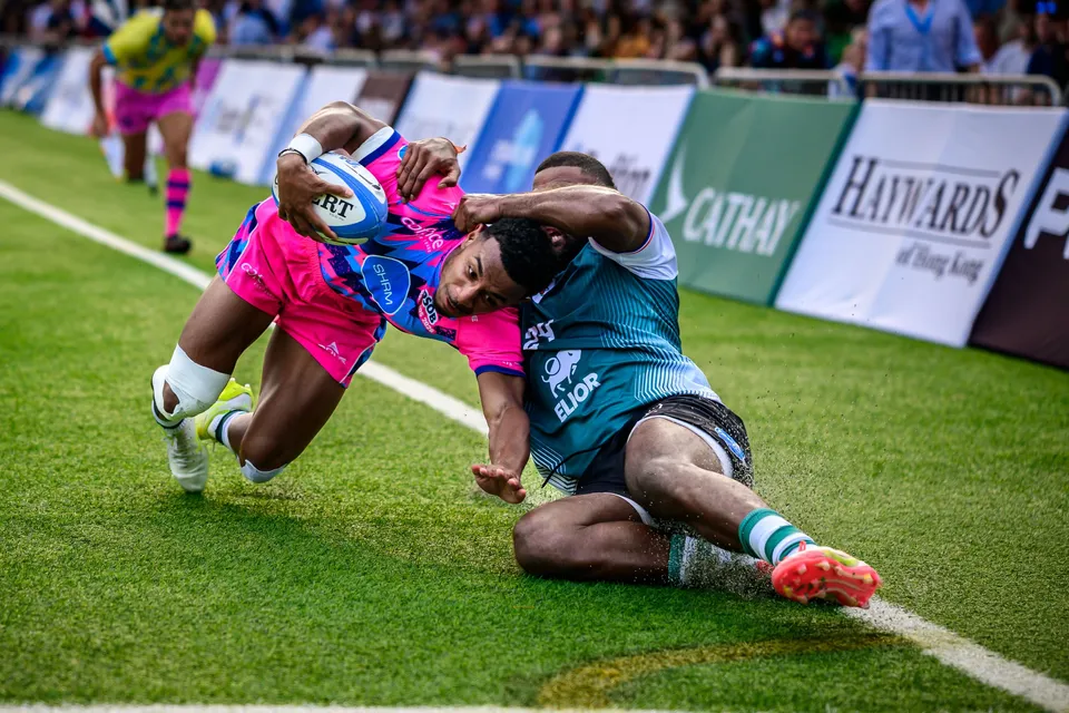 OSOB winger stretches the ball toward the corner as a Froggies Club defender drags him along the touchline