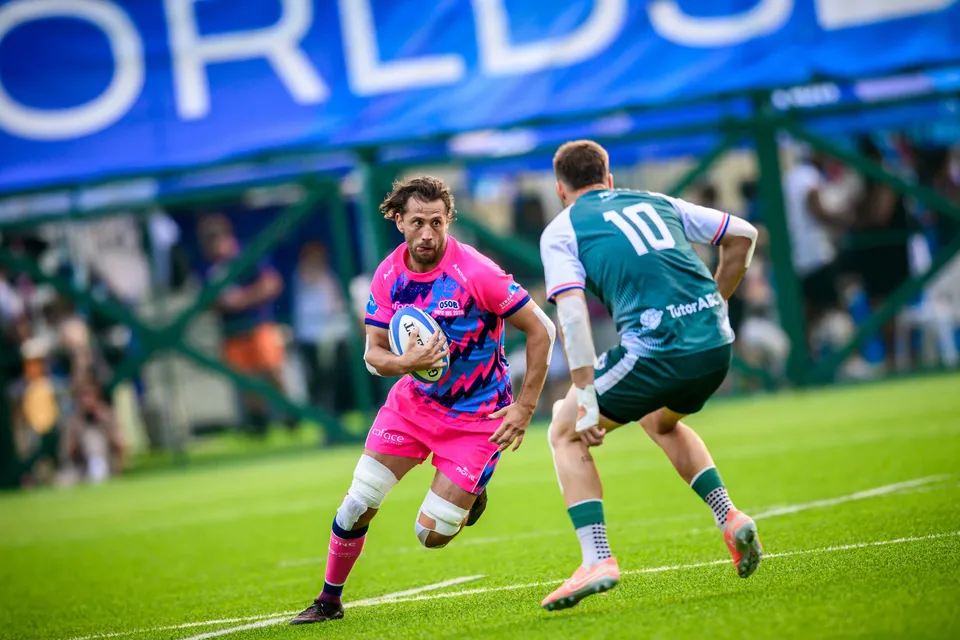 Long-haired OSOB player holds the ball in both hands, facing a Froggies Club defender wearing number 10