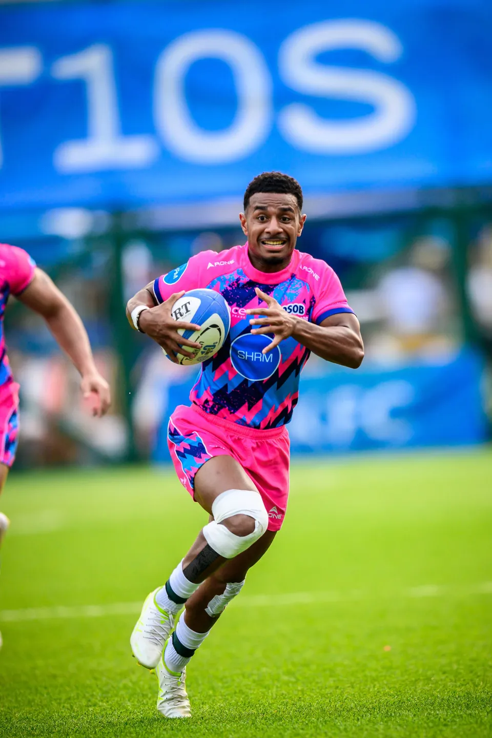OSOB player sprints toward the camera with the ball under one arm, a teammate partly visible beside him