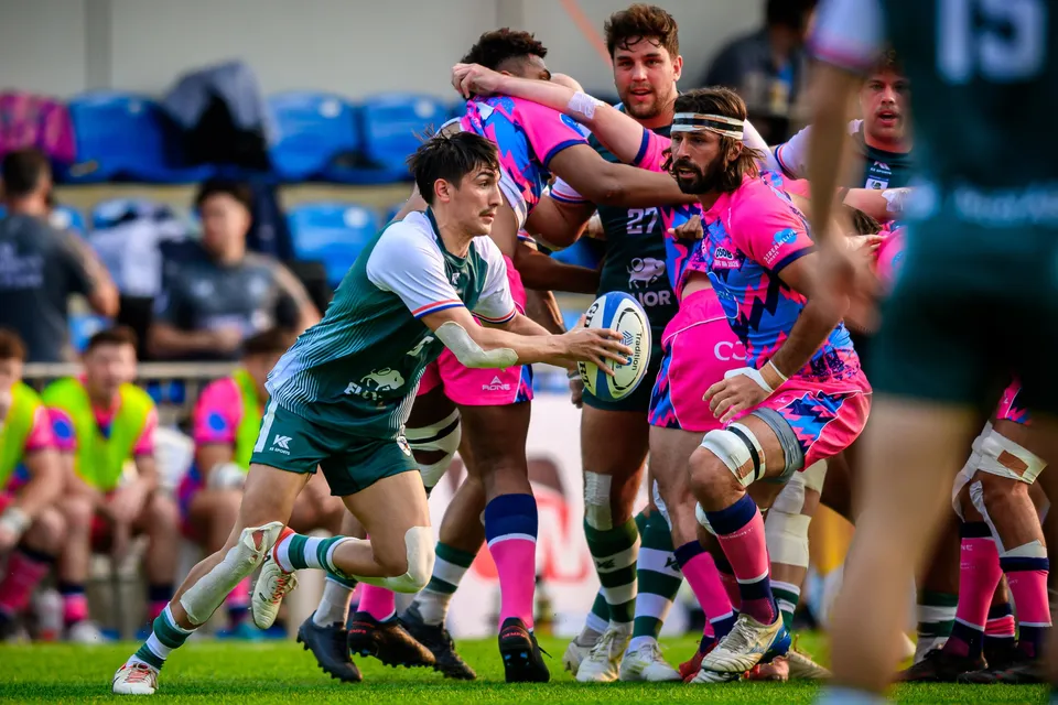 Froggies Club scrum-half in green flicks the ball away from a ruck as OSOB forwards in pink close in