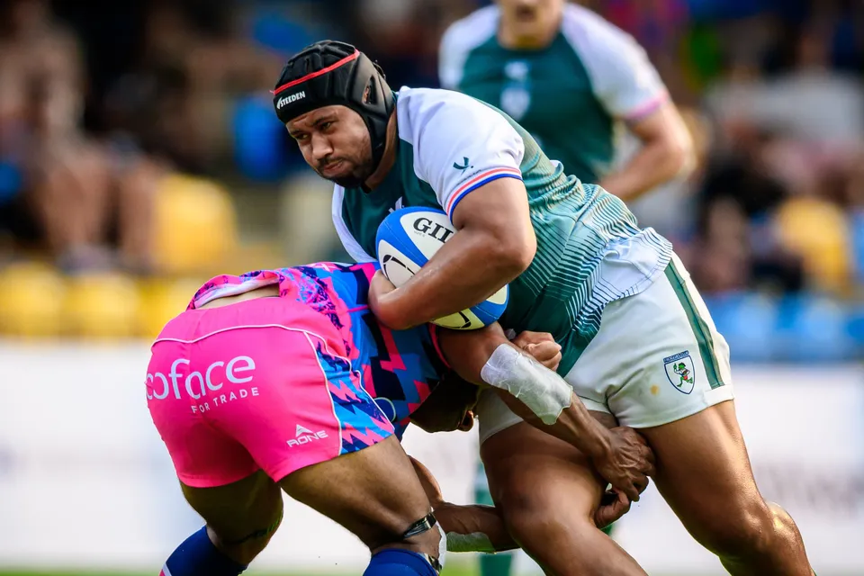 Close-up of a Froggies Club ball carrier in a headguard being tackled around the waist by an OSOB player