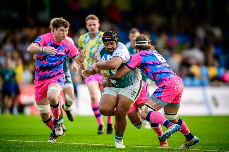 Froggies Club ball carrier in a scrum cap runs between two OSOB defenders while a yellow-shirted referee follows