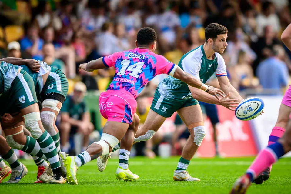 Ball in flight as an OSOB number 14 and a Froggies Club player face each other beside a pack of forwards