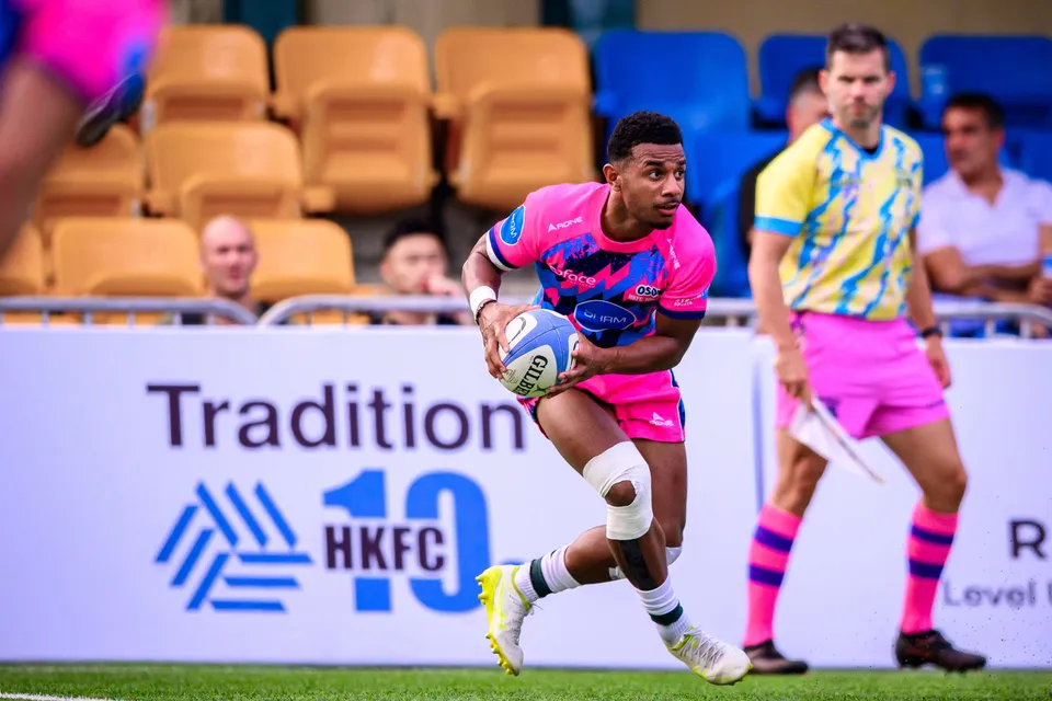 OSOB winger runs along the touchline with the ball in front of a Tradition HKFC 10s board, referee beside him