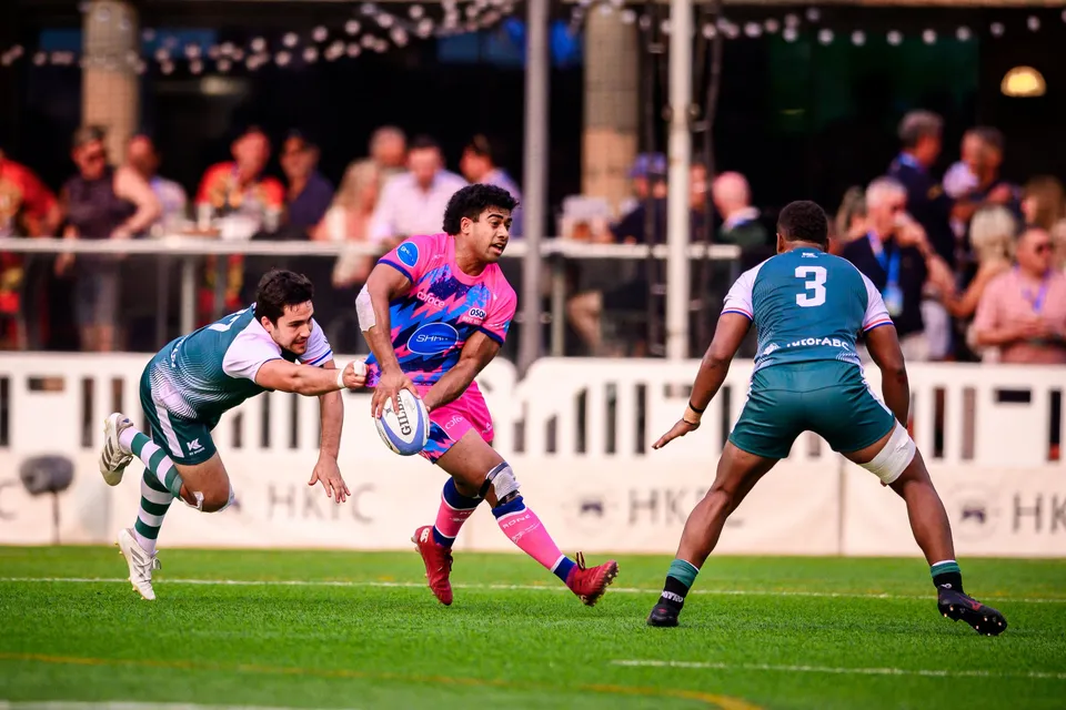 OSOB player offloads the ball as he is tackled in mid-air, Froggies Club number 3 closing in beside him