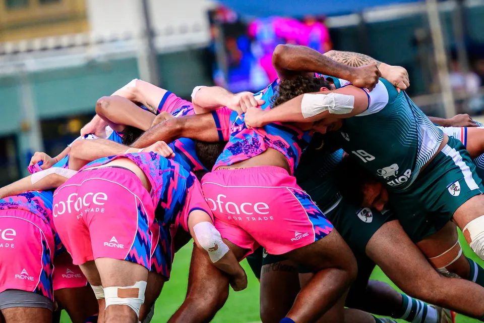 OSOB forwards in pink and blue bind tightly in a scrum against the Froggies pack in dark green and white