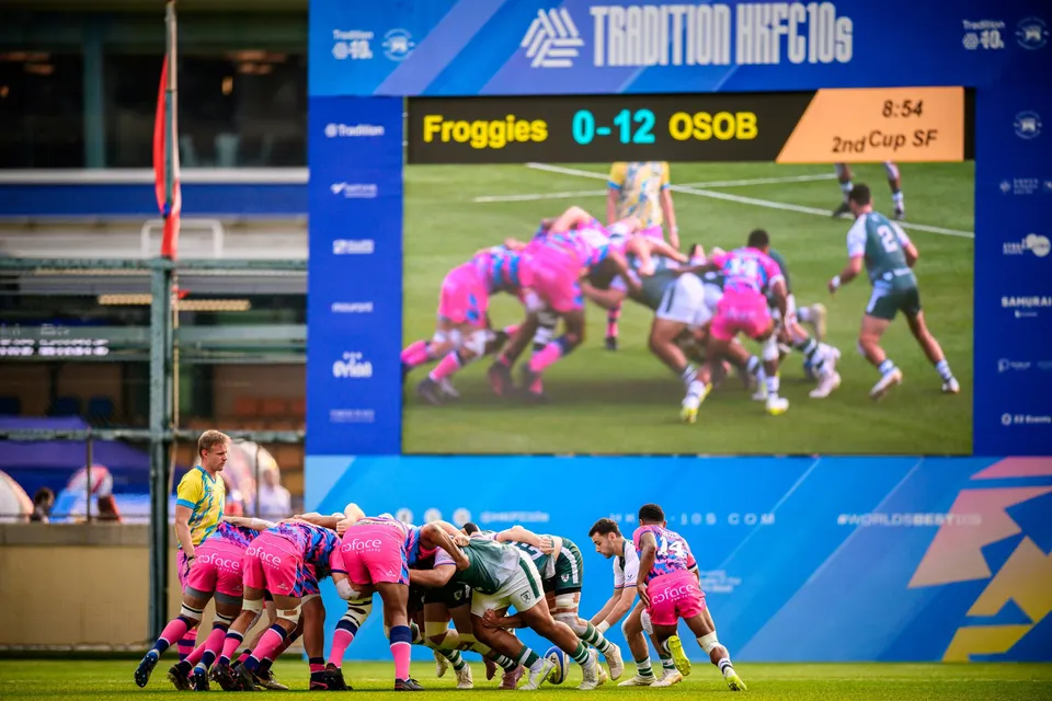 OSOB and Froggies Club forwards bound in a scrum beneath a big screen showing the scoreboard