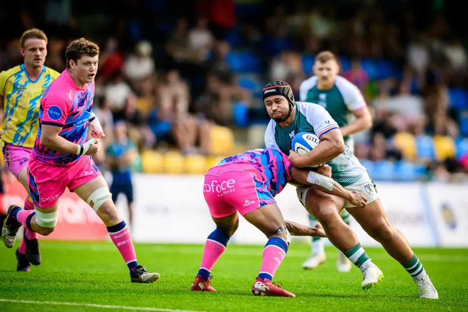 Froggies Club player in a headguard bursts forward with the ball as an OSOB defender tackles low