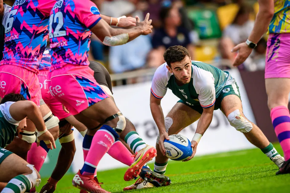 Froggies Club scrum-half crouches with the ball at a ruck as OSOB players in pink drive over beside him