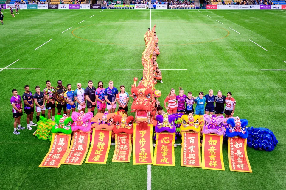 Overhead view of players from several teams lined up beside a long gold dragon and lion heads, 2026 opening ceremony