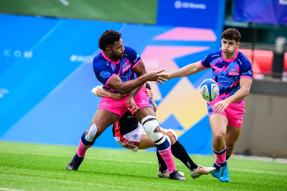 OSOB player is tackled by a black-shirted opponent while flicking the ball out to a team-mate at the HKFC 10s