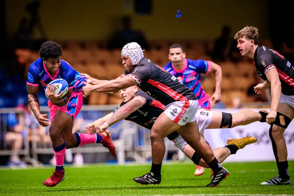 OSOB ball carrier in pink and blue sprints as two black-shirted RGH Shogun defenders dive in to tackle