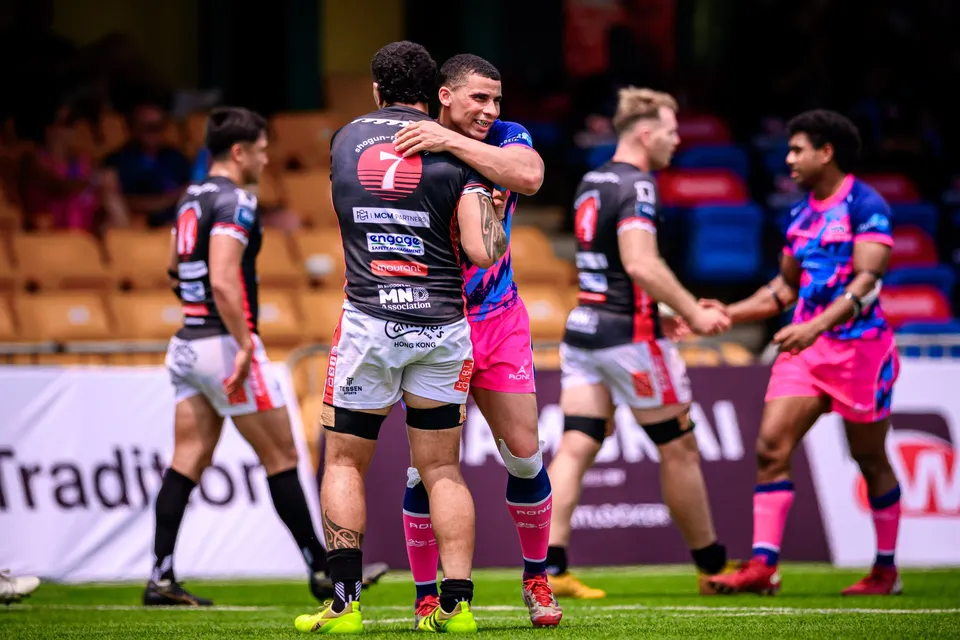 RGH Shogun player wearing number 7 embraces an OSOB player in pink shorts while teammates stand behind