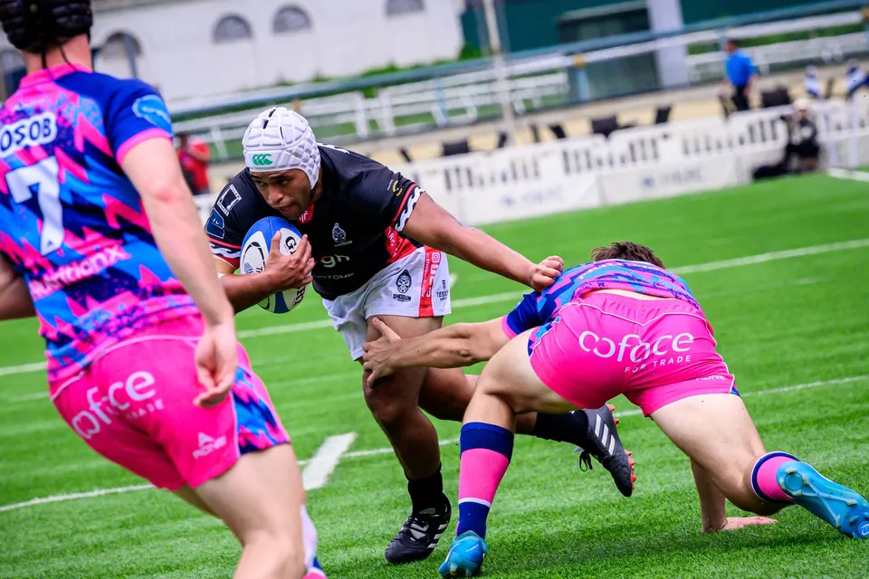 RGH Shogun player in a white headguard carries the ball towards camera as OSOB players close in, one diving low