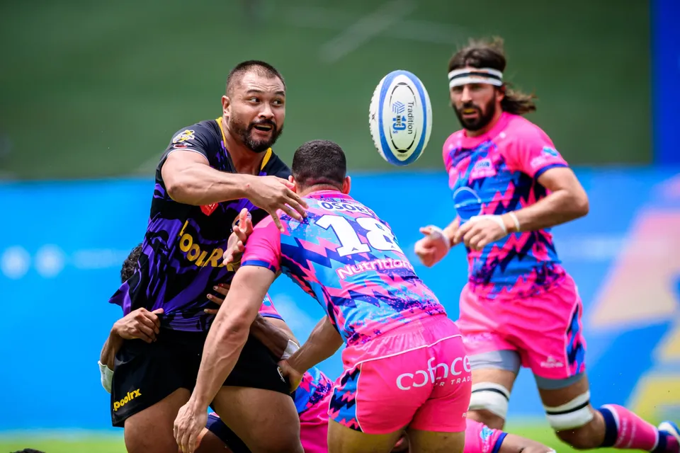 OSOB number 18 reaches across a purple-kit opponent as the ball flies past, a bearded team-mate beside him