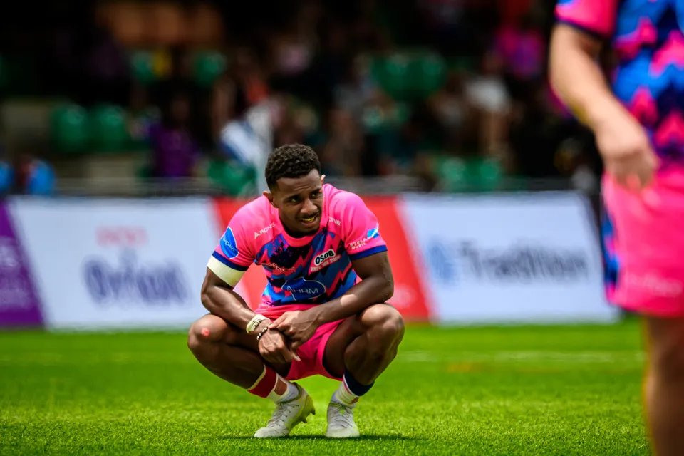 OSOB player crouches head down on the pitch with hands clasped, in front of advertising boards