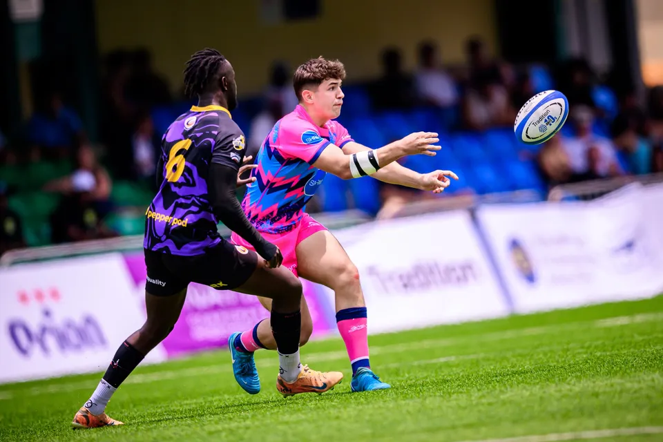 OSOB player with a wrist strap passes the ball with outstretched arms as a purple number 6 runs past