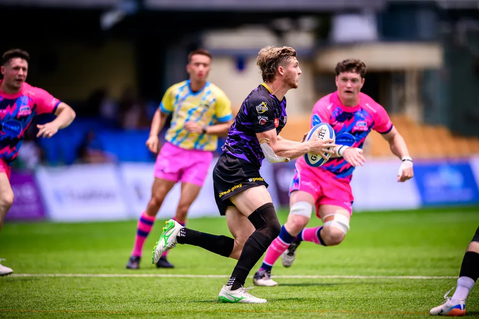 Blond Rugby Tens Selects player in purple carries the ball in one hand as OSOB players close in beside him