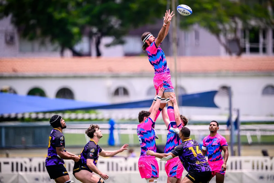 OSOB line-out jumper is lifted high by two team-mates and reaches for the ball, with a purple-kit player alongside