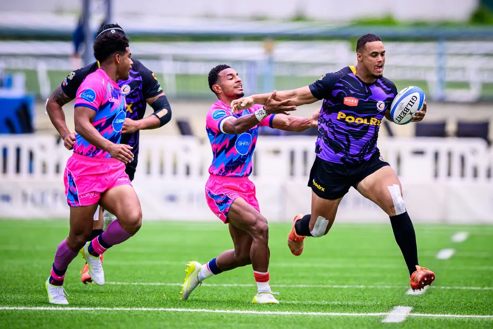 Tens Selects player in purple passes in open play as two OSOB players in pink and blue rush at him